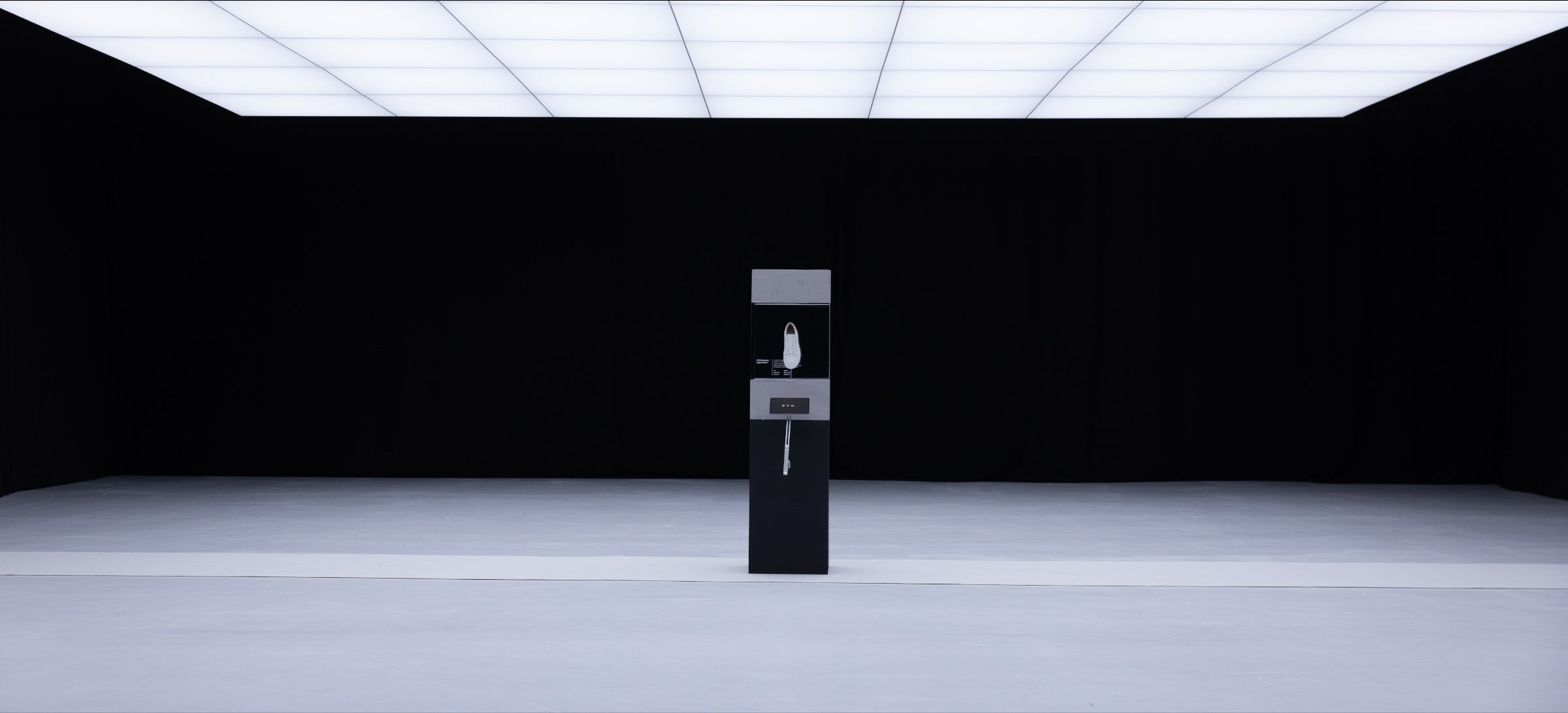An ETQ sneaker on a pedestal in an empty gallery
